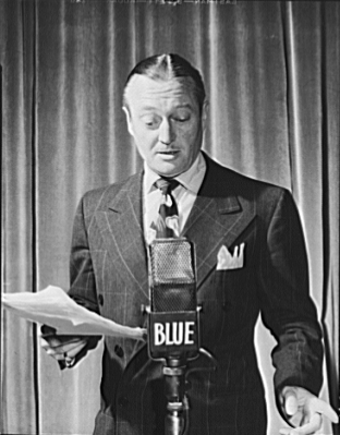 Edmund Lowe，美國演員，站在標有 (NBC) 藍網的廣播麥克風前，手持劇本，1942